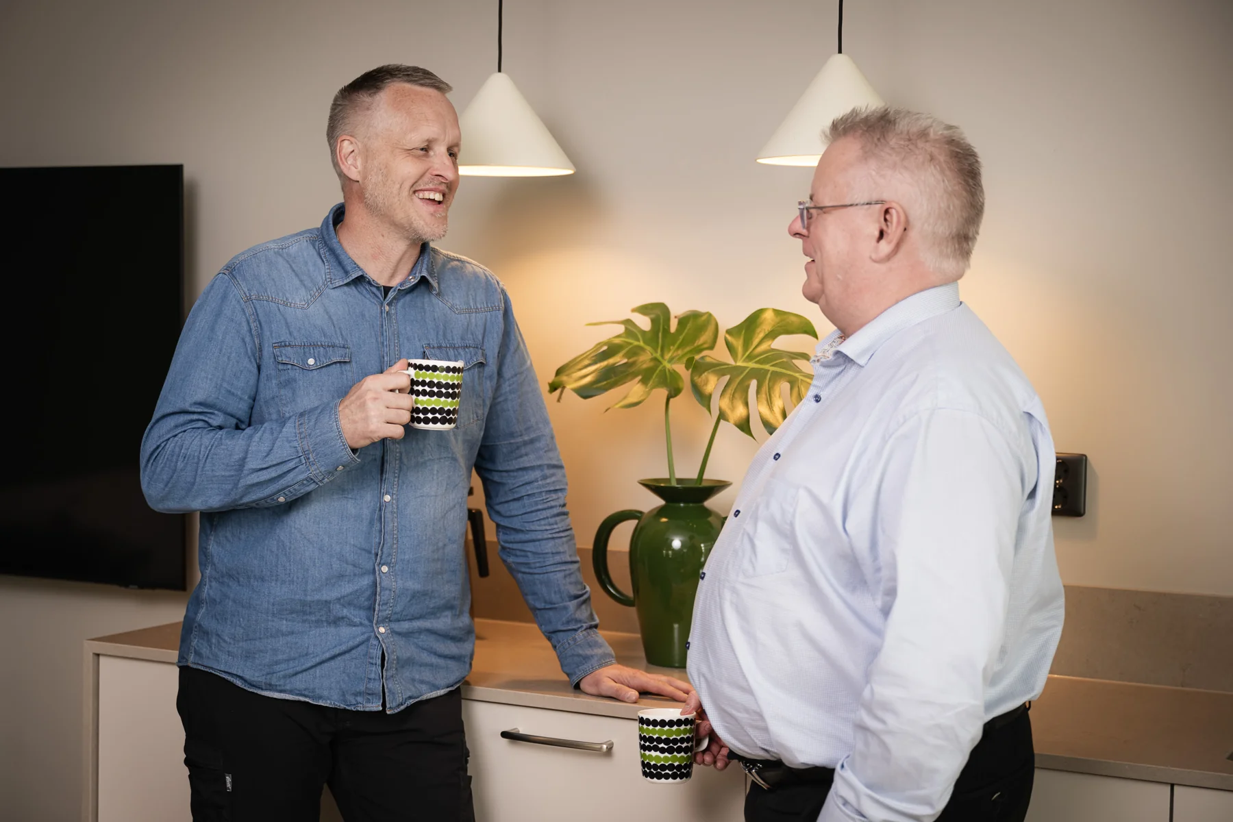 Två kollegor med kaffekoppar i samtal på kontoret