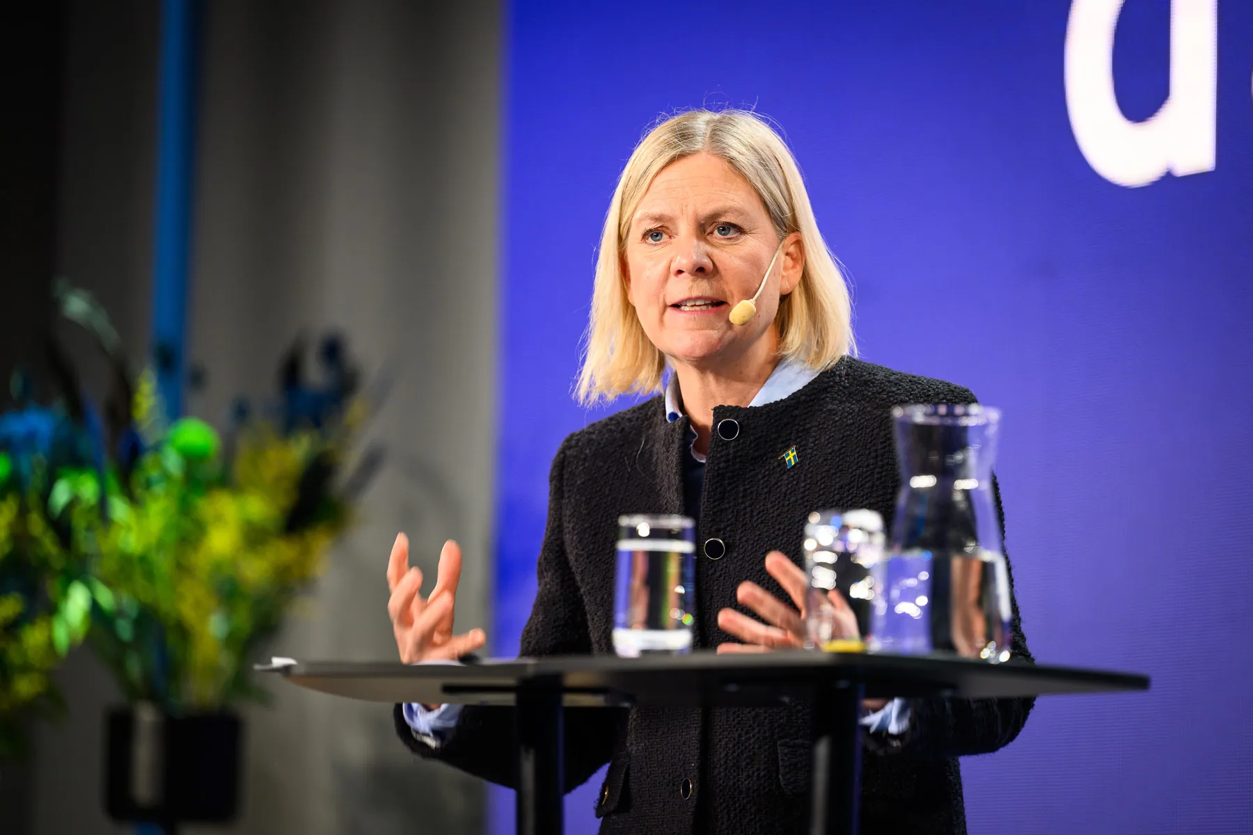Kvinna som talar på scen framför en blå bakgrund